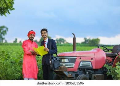 Young Indian Bank Officer Showing Detail Of Loan Paper To Farmer At Field