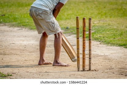 A young Indian boy playing cricket. View of a right handed batsman with all three stumps visible. - Shutterstock ID 1586441224