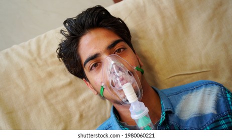 Young Indian Boy Taking Emergency Oxygen With Cannula Outside Of Hospital. Severe Causes Due To Covid In India Concept