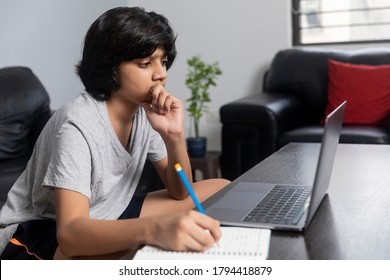 Young Indian Boy Taking Notes From Laptop. Teenager Using Computer At Home.