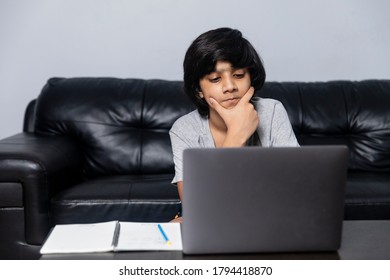 Young Indian boy using laptop. Teenager working on computer at home.