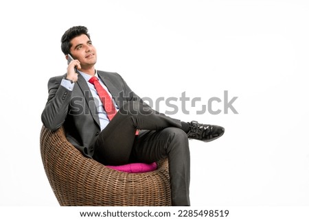 Young indian businessman sitting on chair and talking on smartphone.