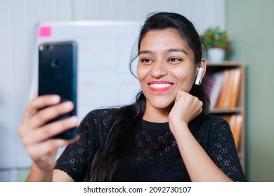 Young Indian Businesswoman Busy Chatting On Video Call From Mobile Phone At Office - Concept Of Wasting Time At Workplace, Distraction From Work And Taking Break