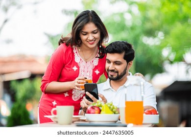 Young Indian couple using smart phone and tablet pc in the outdoor cafe - Powered by Shutterstock