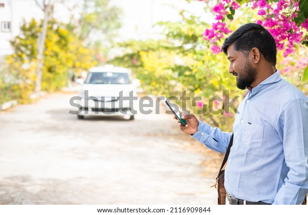 Young indian customber booking cab using\
mobile phone - concept of waiting for cab, online booking service\
and technology