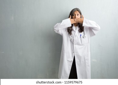 Young indian doctor woman against a wall covering mouth, symbol of silence and repression, trying not to say anything