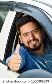 young Indian driver showing thumbs up sitting in car 