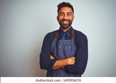 Young Indian Employee Man Wearing Apron Uniform Standing Over Isolated White Background Happy Face Smiling With Crossed Arms Looking At The Camera. Positive Person.