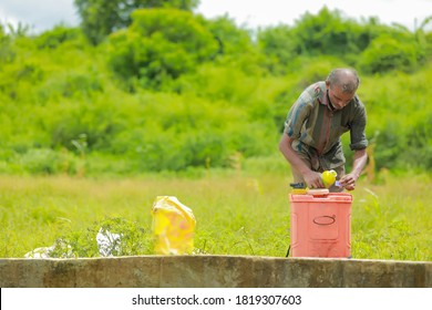 young indian farmer with spray pump and pesticide