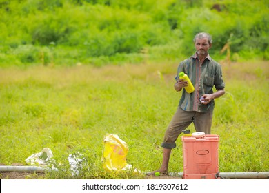 young indian farmer with spray pump and pesticide