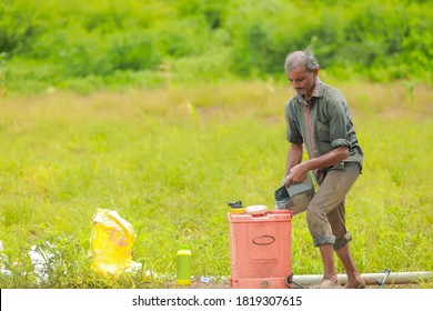 young indian farmer with spray pump and pesticide