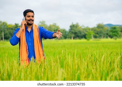 Young Indian Farmer Talking On Mobile Phone At Green Rice Field