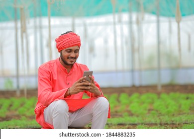 Young Indian Farmer Using Smart Phone At Greenhouse