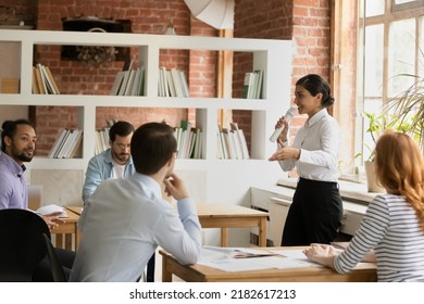 Young Indian female business coach makes speech into microphone for group of diverse company staff employees during educational seminar conference in modern office. Corporate training event concept - Powered by Shutterstock