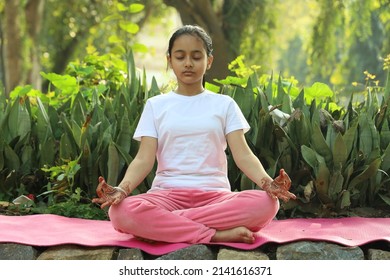 Young Indian female child practicing  yoga in the park in day time. Girl is doing yoga in clean and green environment and fresh air. - Powered by Shutterstock