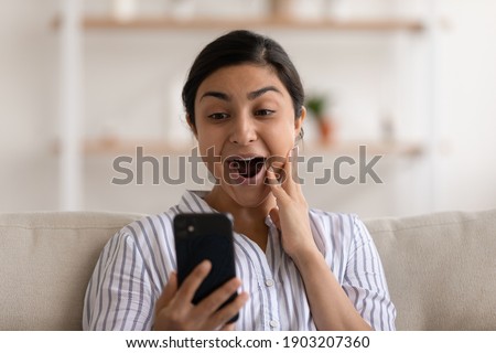 Young indian female shocked by unexpected pleasant surprise in electronic letter on cellphone screen. Happy overwhelmed mixed race woman excited with news of being hired accepted to college university