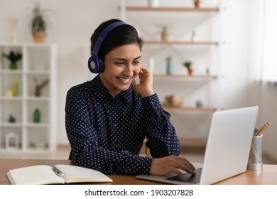 Young Indian Female Student In Headset Sit By Laptop Choose Course Online At Distance Learning Web Platform Of University. Mixed Race Woman Work Study From Home Using Modern Tech Internet Advantages