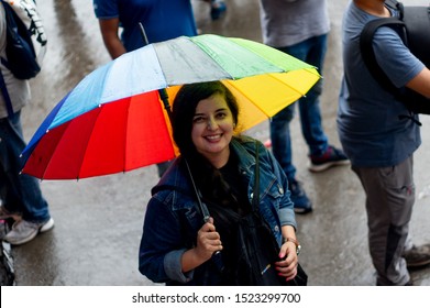 Young indian girl with a colorful umbrella standing on a foggy street in himachal pradesh. Shows the fun and happiness of a travel trip in india during the holidays