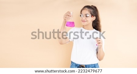Young indian girl student doing science experiment holding colorful chemical flask isolated over beige background. Education concept.