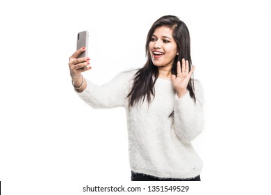 Young Indian Girl Using A Mobile Phone Or Smartphone, Talking Selfie Or Talking On Video Chat On A White Background