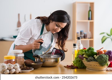 Young Indian Housewife Looking Into A Saucepan