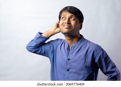 A Young Indian Male In Blue Dress Scratching Head And Thinking On White Background