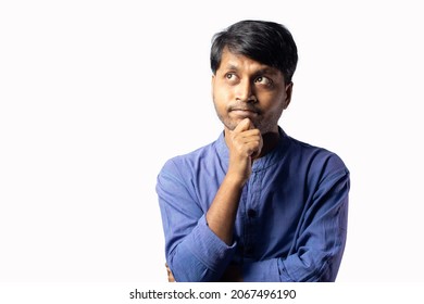 A Young Indian Male In Blue Ethnic Dress Posing With Hand Under Chin On White Background