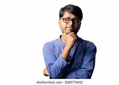 A Young Indian Male In Blue Ethnic Dress And Glasses Posing With Hand Under Chin On White Background