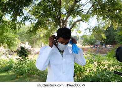 A Young Indian Male Healthcare Worker Putting On A Medical Face Mask Outdoors