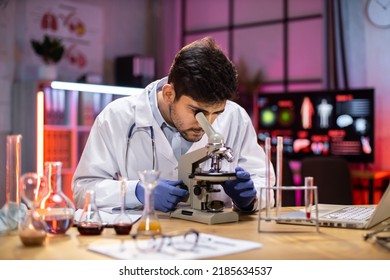 Young indian male researcher looking at the microscope analyze science, forensics, microbiology, biochemistry, genetics, oncology, laboratory. - Powered by Shutterstock