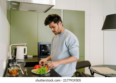 Young Indian Man Cooking Salad On Cozy Kitchen At Home