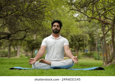 Young indian man doing yoga in park. Yoga and meditation concept. Young guy doing yoga lotus pose in a park - Powered by Shutterstock