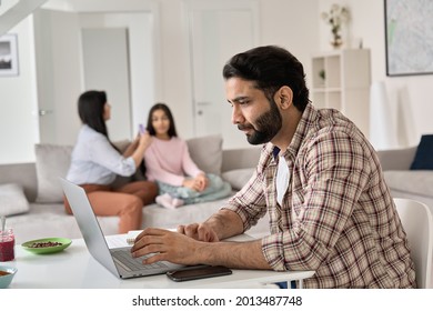 Young indian man father remote working online from home office while his family wife and child daughter spending time at home. Busy parent dad using laptop computer sitting at table in homeoffice. - Powered by Shutterstock