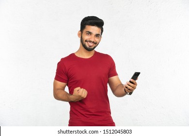 Young Indian Man Holding Phone And Smiling 