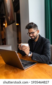 Young Indian Man On Laptop And Coffee At A Cafe