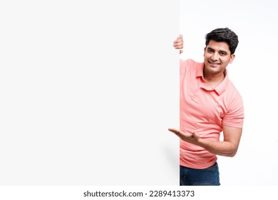 Young indian man showing and pointing of big white board with copy space