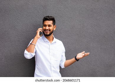 Young Indian Man Smiling Happy Talking On The Smartphone Leaning On The Wall