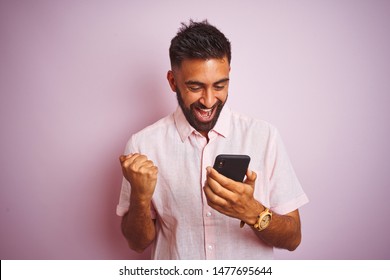 Young Indian Man Using Smartphone Standing Over Isolated Pink Background Screaming Proud And Celebrating Victory And Success Very Excited, Cheering Emotion