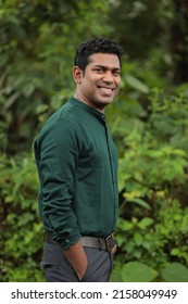 

Young Indian man wearing green shirt standing over green background smiling and looking at the camera  - Shutterstock ID 2158049949