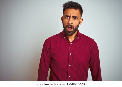 Young Indian Man Wearing Red Elegant Shirt Standing Over Isolated Grey Background In Shock Face, Looking Skeptical And Sarcastic, Surprised With Open Mouth