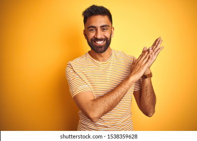 Young Indian Man Wearing T-shirt Standing Over Isolated Yellow Background Clapping And Applauding Happy And Joyful, Smiling Proud Hands Together