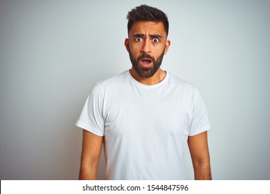 Young Indian Man Wearing T-shirt Standing Over Isolated White Background In Shock Face, Looking Skeptical And Sarcastic, Surprised With Open Mouth