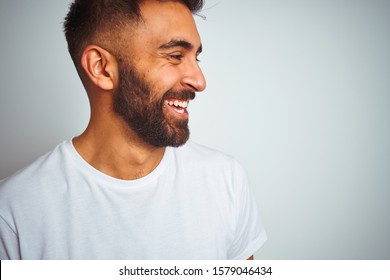 Young Indian Man Wearing T-shirt Standing Over Isolated White Background Looking Away To Side With Smile On Face, Natural Expression. Laughing Confident.