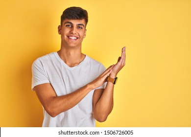 Young Indian Man Wearing White T-shirt Standing Over Isolated Yellow Background Clapping And Applauding Happy And Joyful, Smiling Proud Hands Together