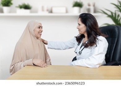 Young indian muslim woman wearing hijab consults about her problem with female gynecologist doctor in modern clinic. - Powered by Shutterstock