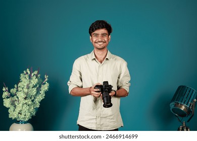 Young Indian photographer is taking a photo. Model isolated on a background with copy space. Cheerful photographer with beard, while working in studio - Powered by Shutterstock