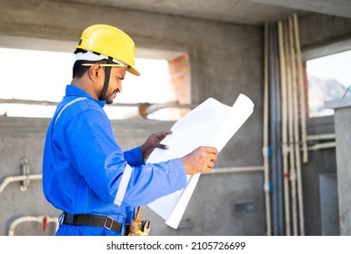 young indian plumber or engineer checking construcation planning map by seeing at workplae - concept of blue collar worker and construcation service. - Shutterstock ID 2105726699