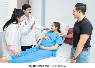 Young Indian Pregnant Woman With Her Husband Visiting Or Consulting Doctor At The Hospital, Pregnancy Checkup.