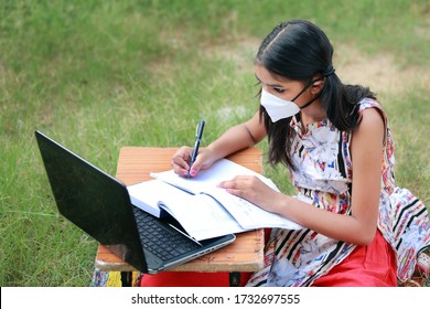 A young Indian rural girl wearing mask is studying online.Study in lock down. Online school classes. Schools closed due to Covid-19. Role of technology during nationwide lock down.Learning at home. 