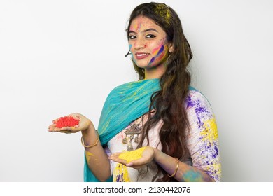 Young indian smart girl with color powder in her hand and with face coloured with gulal for festival of colours Holi, a popular hindu festival celebrated across india, isolated over white background - Powered by Shutterstock